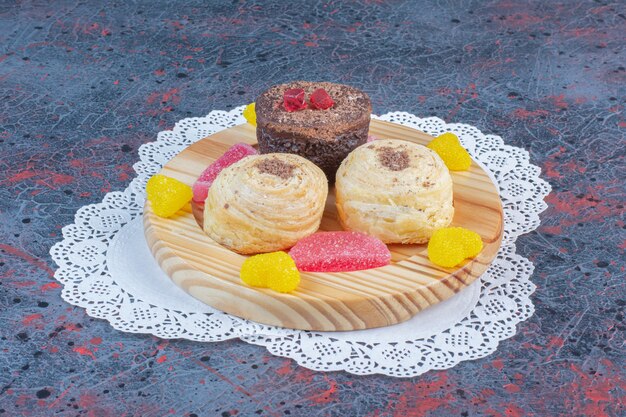 Paquete de tortas y mermeladas en una bandeja de madera sobre tabla abstracta.