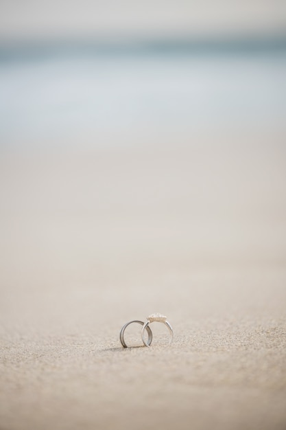 Foto gratuita par de anillo de bodas en la arena