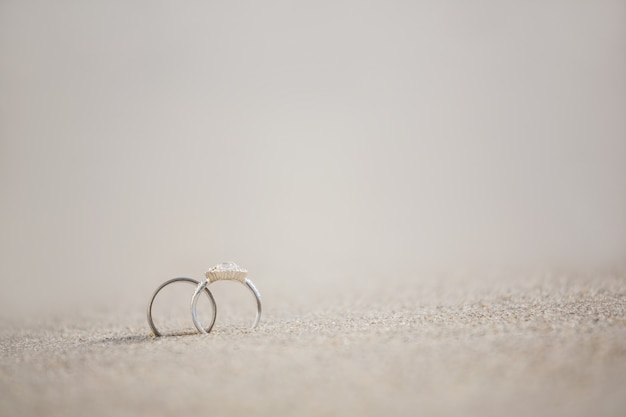 Foto gratuita par de anillo de bodas en la arena