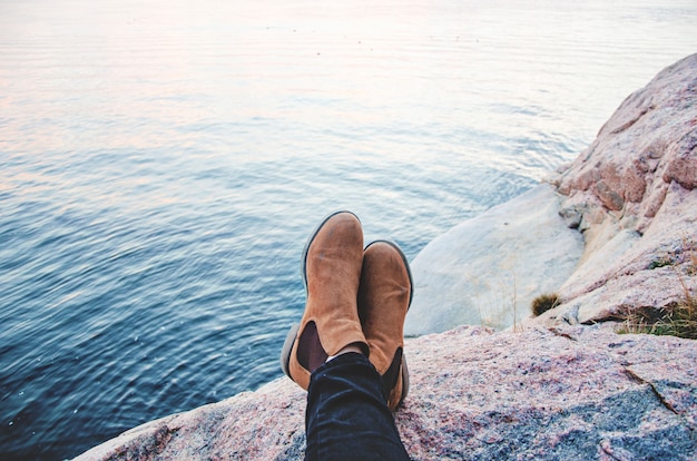 Foto gratuita un par de botas descansando en una montaña frente al mar.