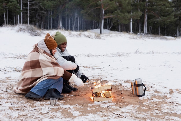 Par calentar junto al fuego en la playa durante un viaje por carretera de invierno