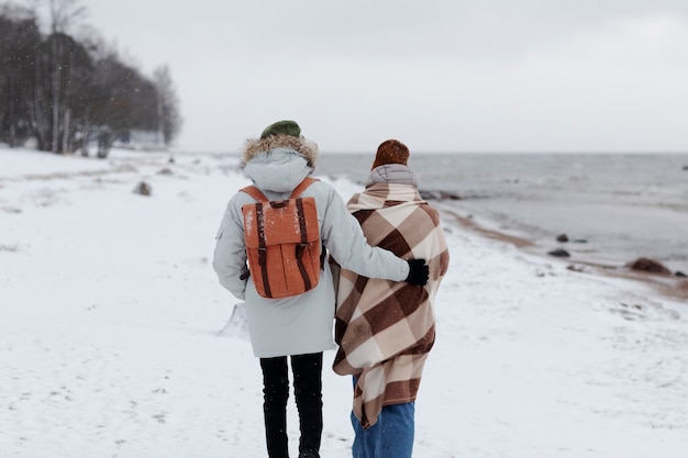 Par despertar juntos en la playa durante un viaje por carretera de invierno