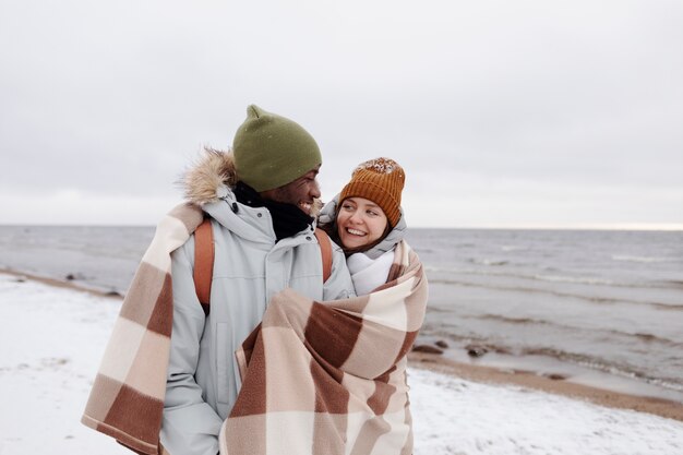 Par despertar juntos en la playa durante un viaje por carretera de invierno