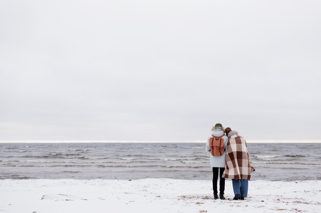 Par despertar juntos en la playa durante un viaje por carretera de invierno