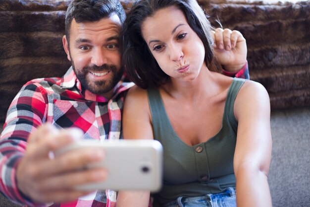 Par hacer expresión divertida mientras toma selfie en teléfono móvil