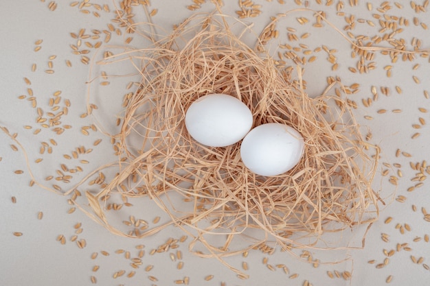 Foto gratuita par de huevos de gallina marrón sobre superficie blanca