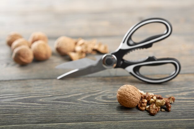Par de tijeras de cocina y nueces abiertas en la mesa de madera abridor de nueces herramienta instrumento nutrición alimentaria útil concepto de alimentación.