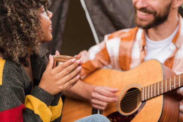 Par tocando la guitarra mientras acampa afuera