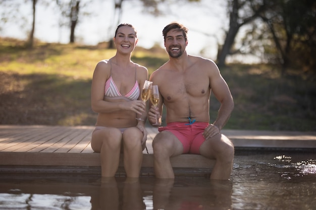 Par tostado copas de champagne en la piscina