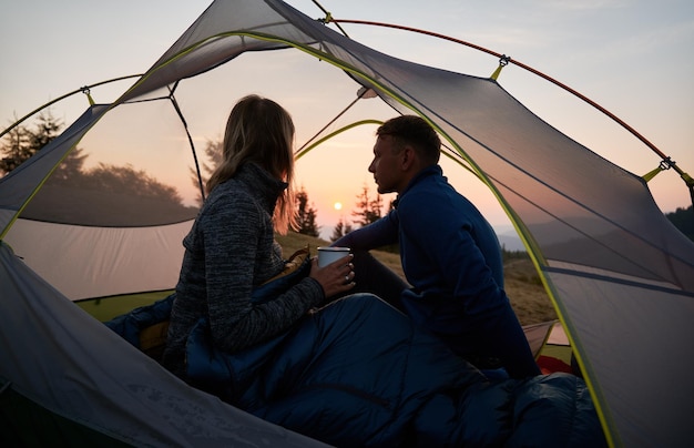 Un par de turistas descansando en una carpa al aire libre