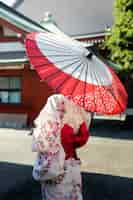 Foto gratuita paraguas wagasa japonés ayudado por mujer joven