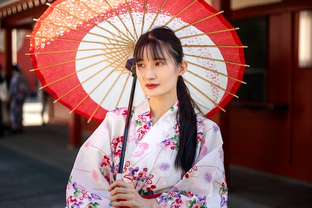 Foto gratuita paraguas wagasa japonés ayudado por mujer joven