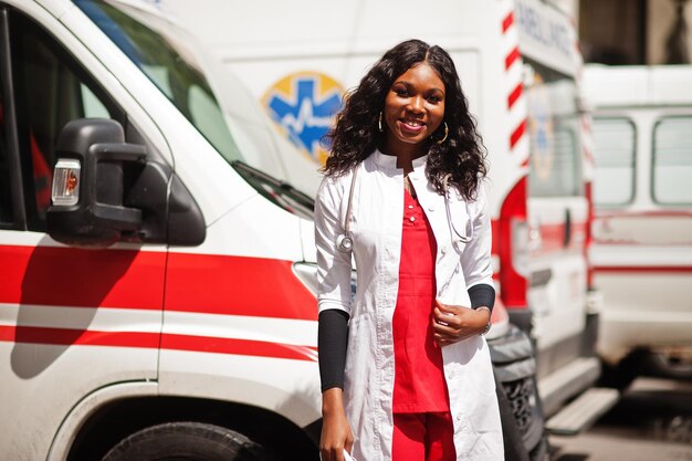 Foto gratuita paramédico mujer afroamericana de pie delante del coche de ambulancia