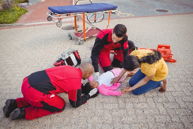 Foto gratuita paramédicos examinando niña herida