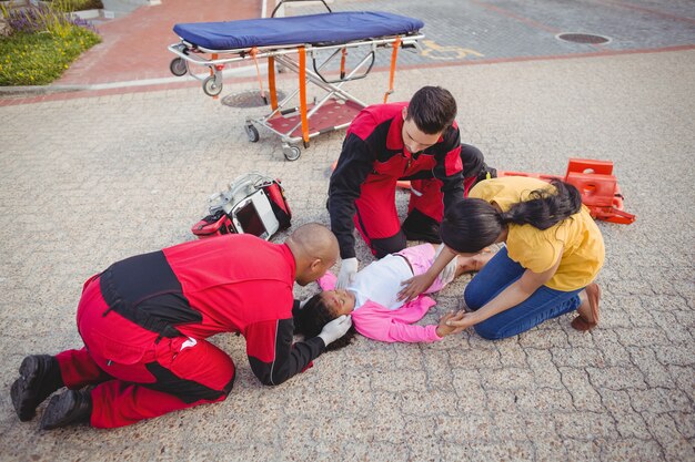 Paramédicos examinando niña herida