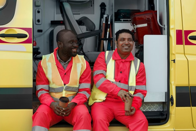 Paramédicos sonrientes de tiro medio con tazas de café.