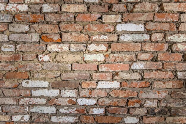 Pared de un antiguo edificio de ladrillo con yeso pelado y superficie pintada.