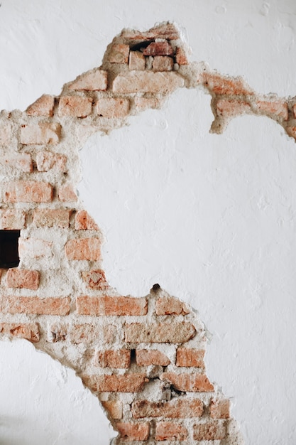 Una pared blanca de hormigón agrietada con ladrillos