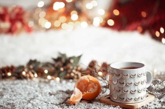 Pared de invierno acogedor con una hermosa taza y mandarina con bokeh.