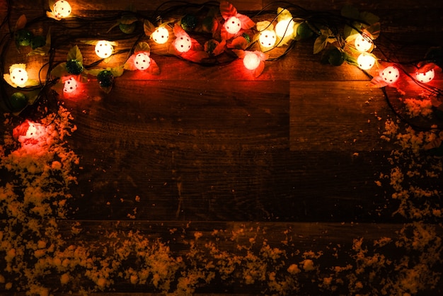 Pared de madera oscura con luces y nieve