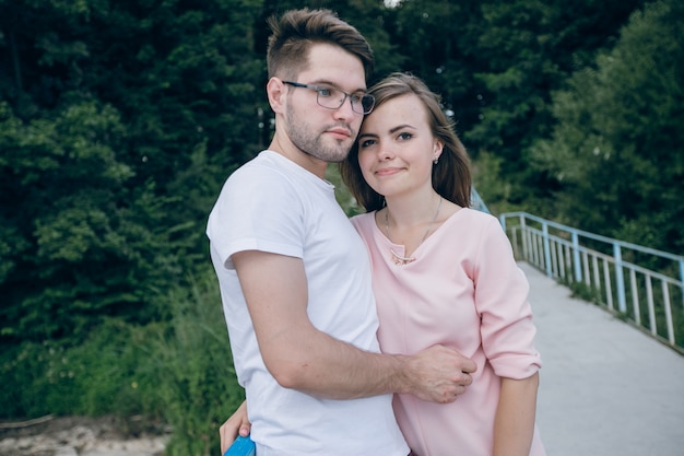 Pareja abrazada y apoyada en un puente con una valla azul