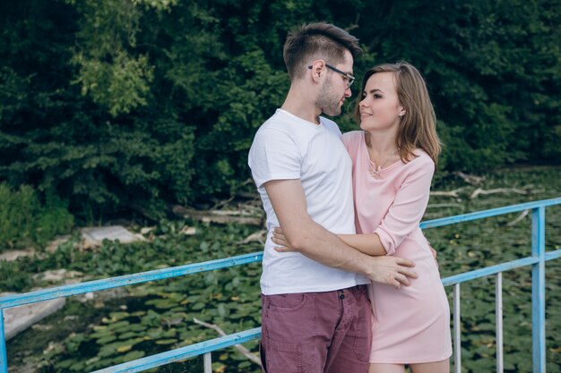 Pareja abrazada apoyada en una valla azul en un puente