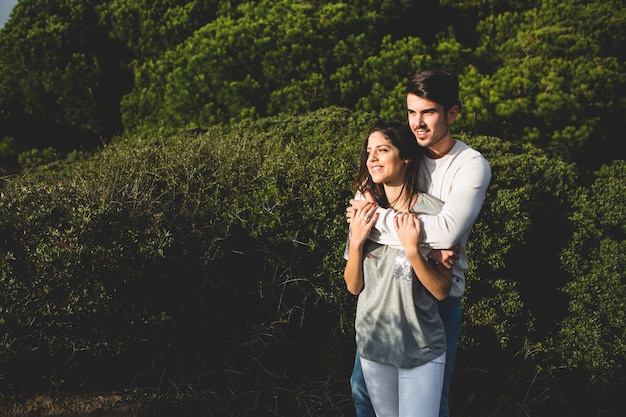 Pareja abrazada con un bosque con árboles detrás