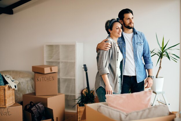 Pareja abrazada disfrutando de la vista desde su nuevo hogar