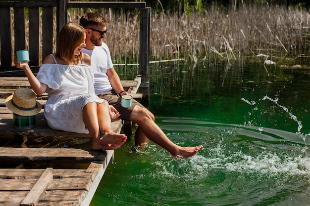 Pareja abrazada jugando con los pies en el agua