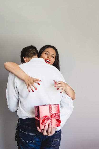 Pareja abrazada y el novio con un regalo en la espalda