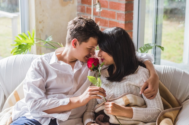 Pareja abrazada en un sofá con una rosa en la mano