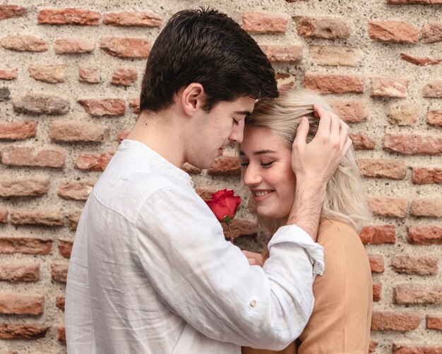 Pareja abrazados mientras posando con rose