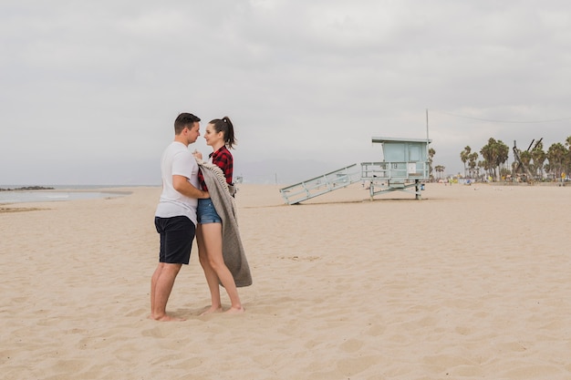 Foto gratuita pareja abrazados en la playa y posando