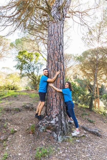 Pareja abrazándose árbol en hermoso bosque