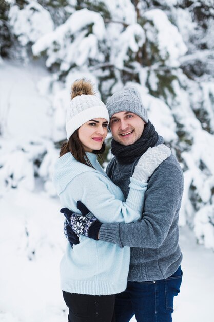 Pareja abrazándose en el bosque de invierno