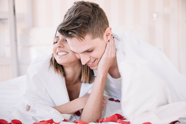 Foto gratuita pareja abrazándose en la cama con pétalos de rosa