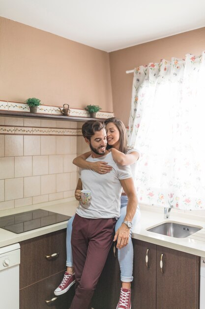 Pareja abrazándose en la cocina por la mañana