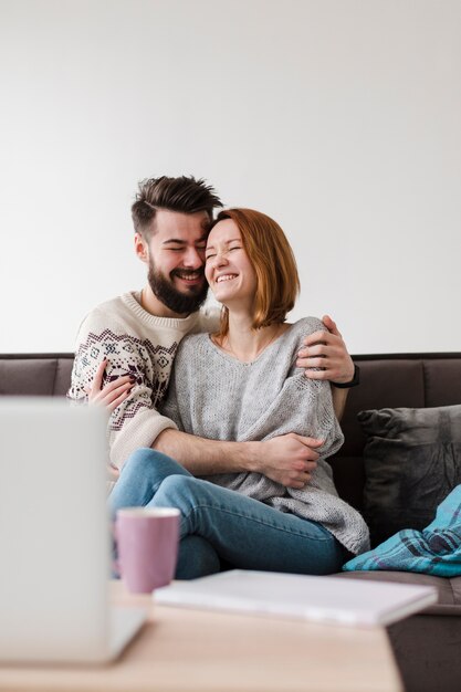 Pareja abrazándose y decoración borrosa con laptop