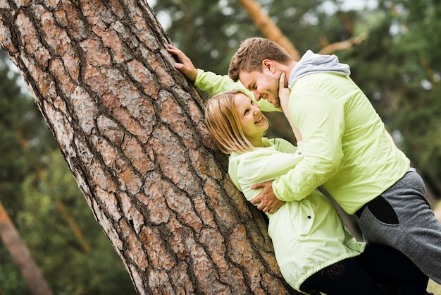 Foto gratuita pareja abrazándose junto a un árbol