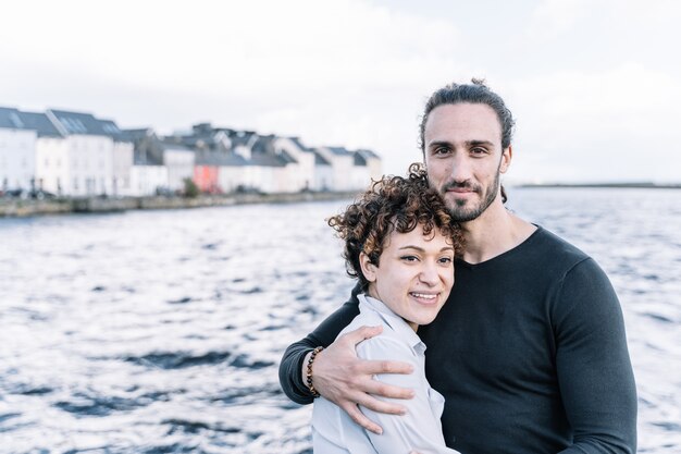 Pareja abrazándose con el mar fuera de foco