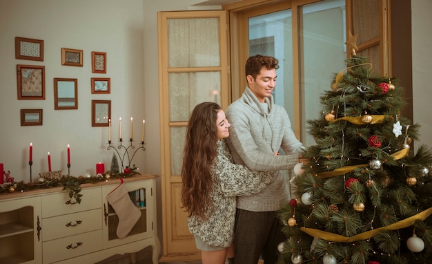 Pareja abrazándose mientras decoraba la casa para navidad