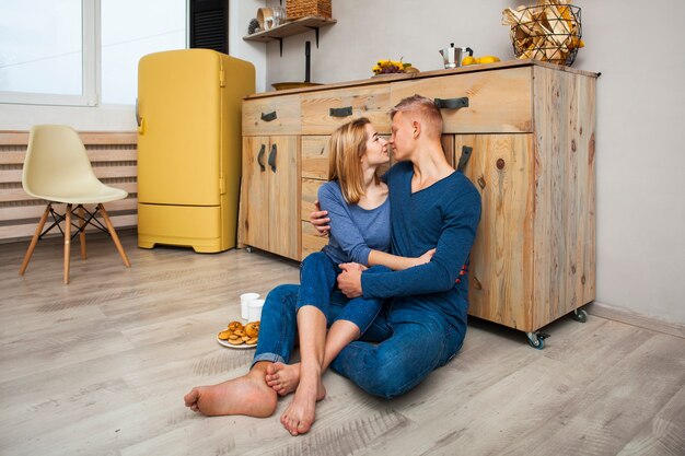 Pareja abrazándose mientras está sentado en el piso de la cocina