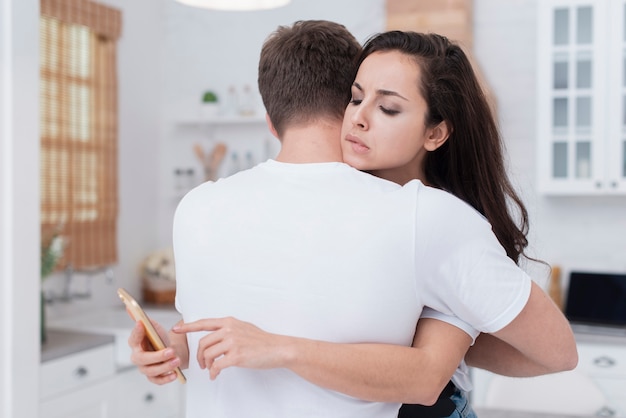 Foto gratuita pareja abrazándose mientras la novia está mirando su teléfono