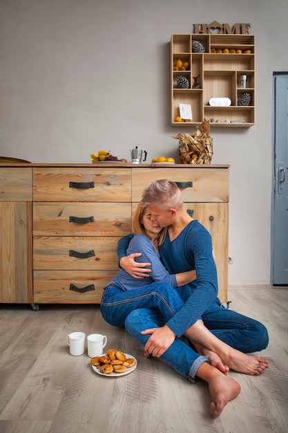 Foto gratuita pareja abrazándose mientras está sentado en el piso