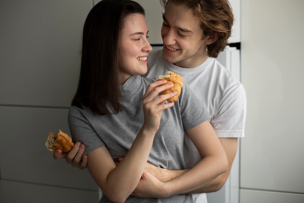 Pareja abrazándose mientras sostiene croissants