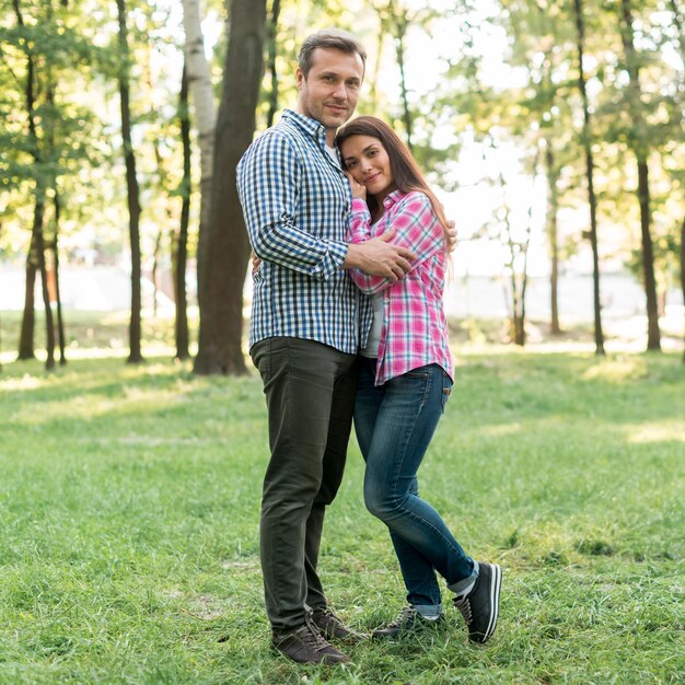 Pareja abrazándose y mirando a cámara en el jardín