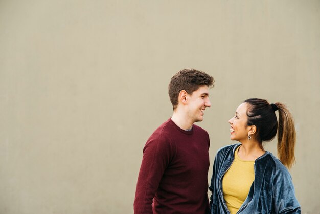 Pareja abrazándose multiétnica sonriendo y mirando el uno al otro