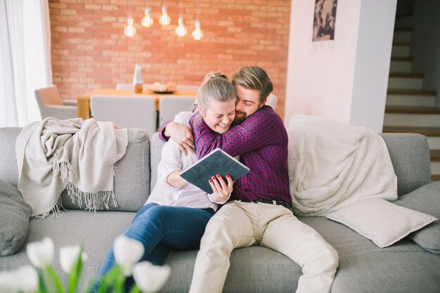 Pareja abrazándose y usando la tableta