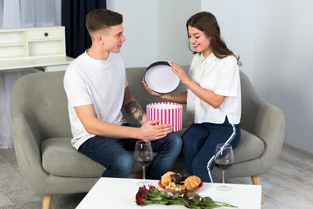 Pareja abriendo una gran caja de regalo en el sofá