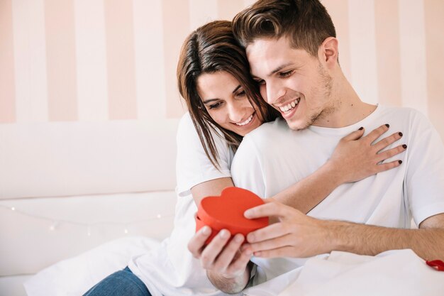 Pareja abriendo presente en la cama